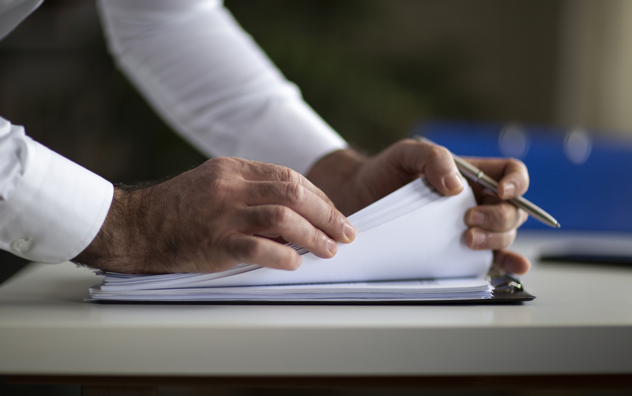 A man flipping through papers on a clipboard
