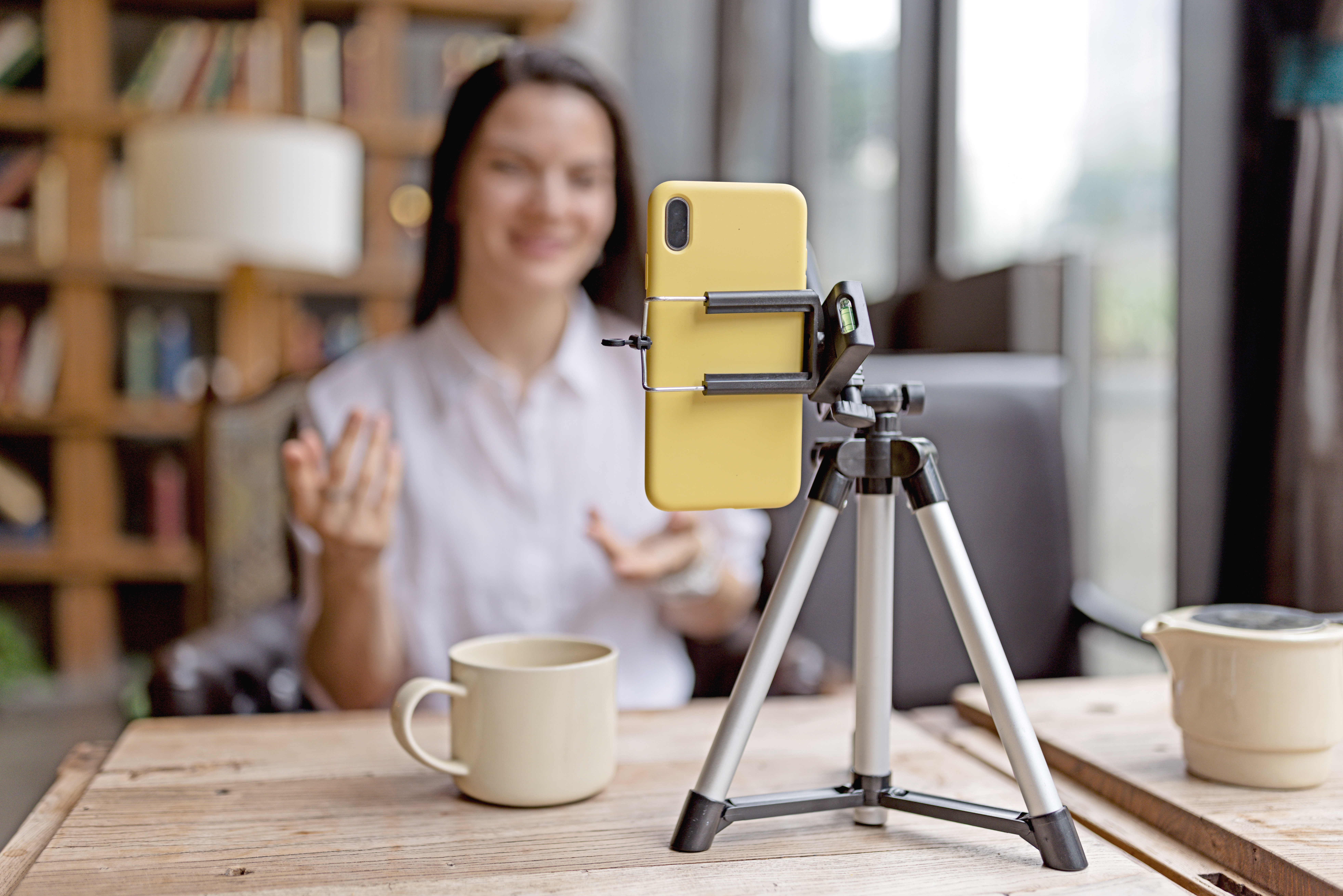 Woman with long brunette hair streaming a video with a smart phone on a tripod